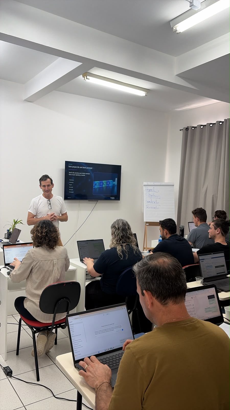 Edney Prigol apresenta as seis peças de um bom prompt enquanto participantes praticam nos notebooks durante o treinamento de IA para negócios